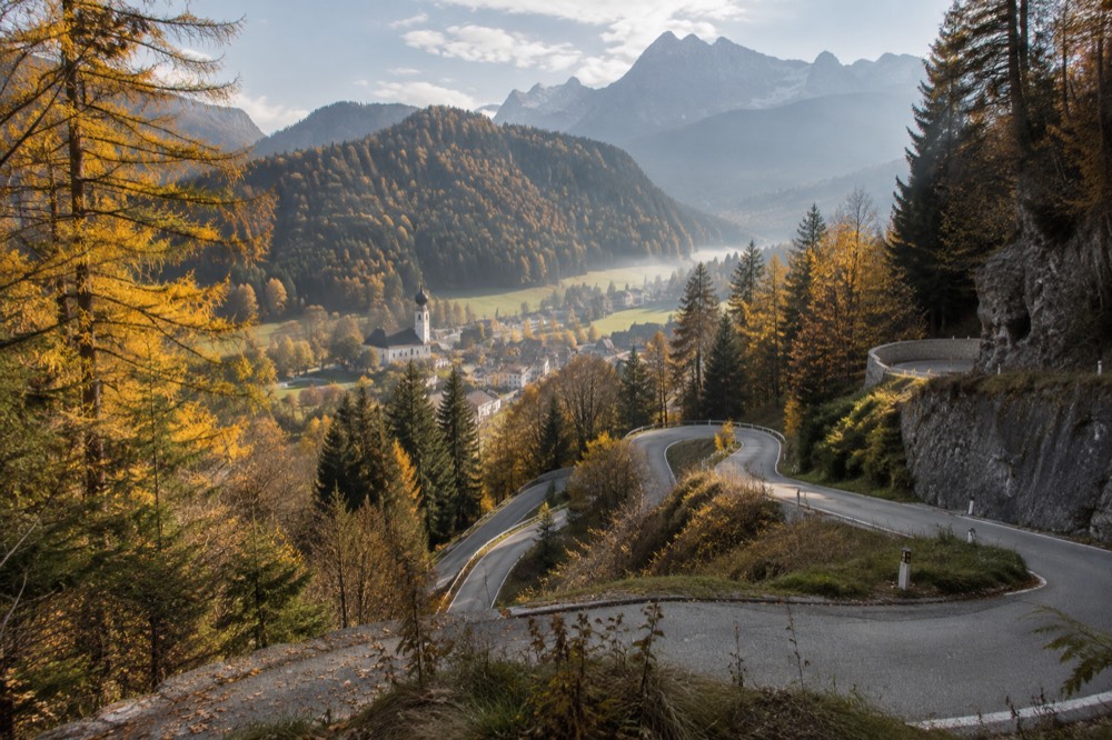 Mountain road winding through alpine scenery with a village in the valley