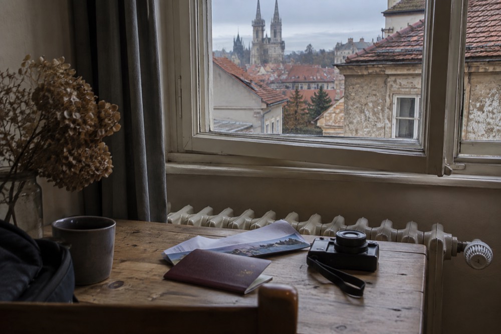 A travellers passport and documents on a wooden table beside a camera