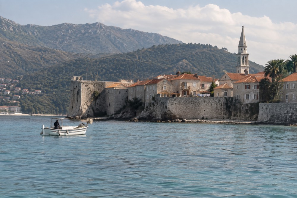 A coastal walled town with terracotta roofs above a calm sea