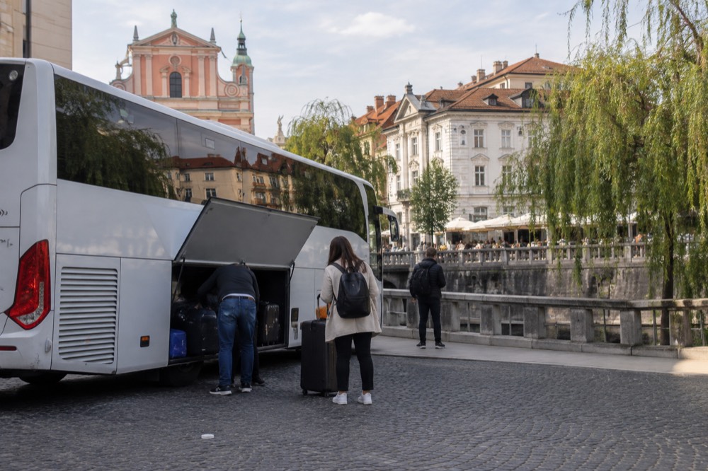 A tour coach parked on a cobbled square beside old European townhouses