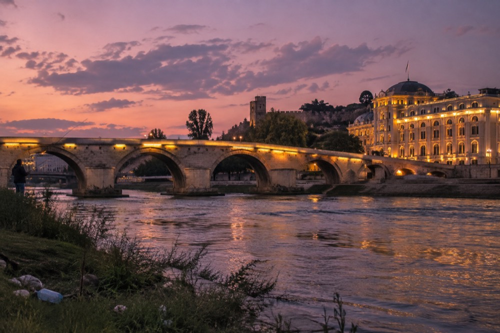 Stone bridge and riverside buildings in a Balkan old town at dusk