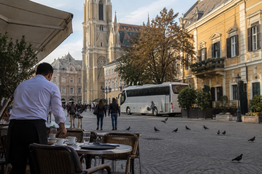 A tour coach parked on a cobbled square beside old European buildings