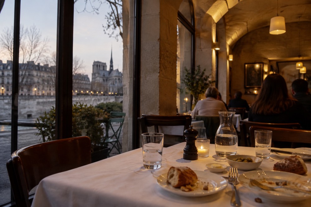 A set dinner table in a European restaurant with bread and water glasses