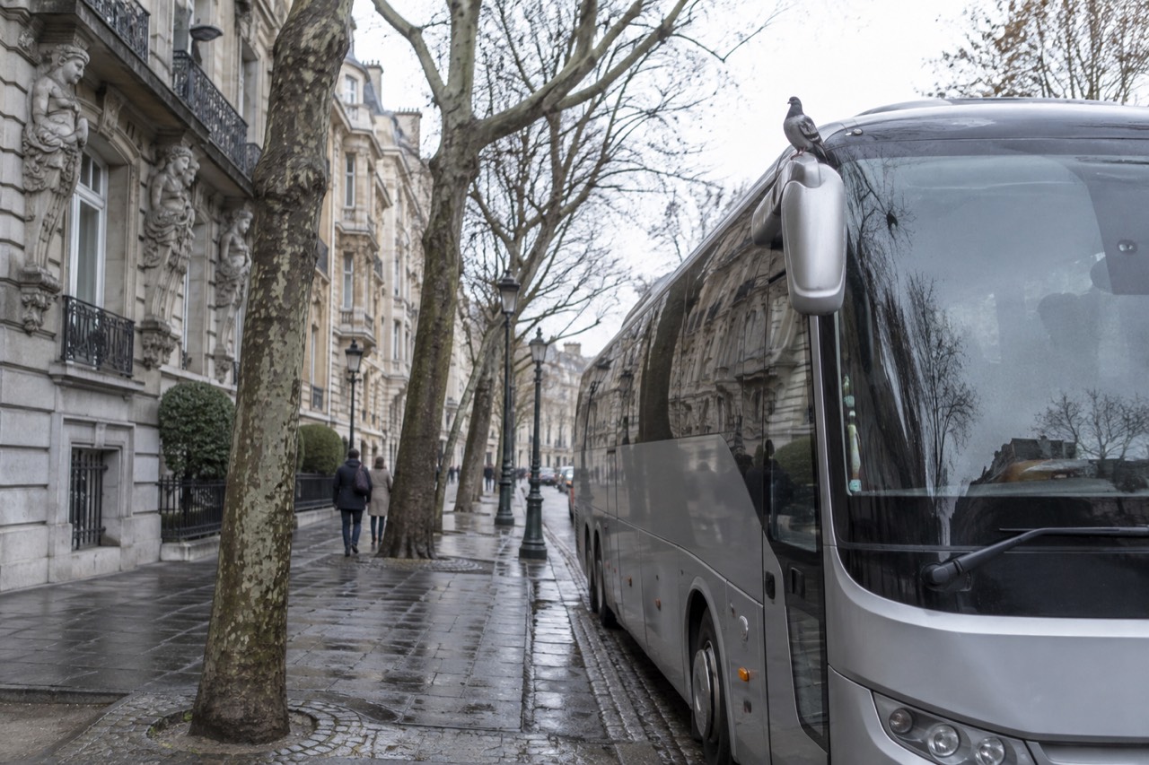 A coach parked on a European boulevard with ornate buildings along the street