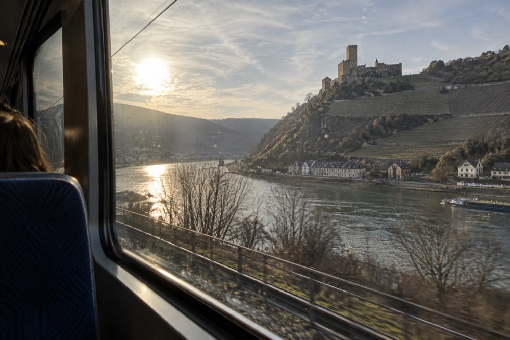 A traveller's view from a train window of a river valley with a hilltop castle